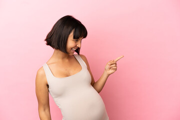 Young pregnant woman over isolated pink background pointing finger to the side and presenting a product