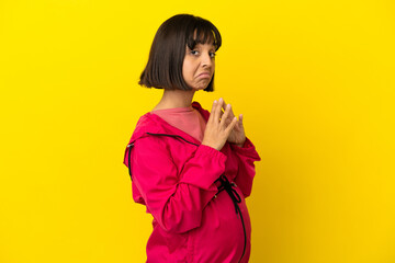 Young pregnant woman over isolated yellow background scheming something