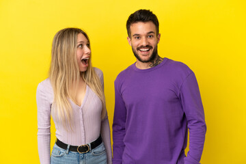 Young couple over isolated yellow background with surprise facial expression