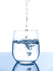 Water pouring into glass. Studio shot. Vertical. Blue light. Motion freeze.