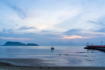 small fishng boat parked at the shore of Prachuap Bay with Khao Ta Mong Lai Forest Park background, Thailand