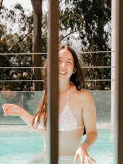Beatiful woman enjoying her time at an aqua color pool with a white bikini.