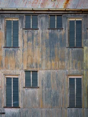 Foto op Plexiglas Oude verlaten gebouwen Ramen en de golfplaten muur van een verlaten fabriek