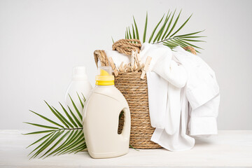 Wicker basket with white linen, clothespins, clothesline, washing gel and fabric softener on a...