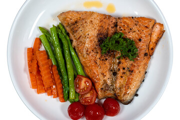Close-up Salmon steak with vegetables, asparagus, carrots, green peas, pepper.