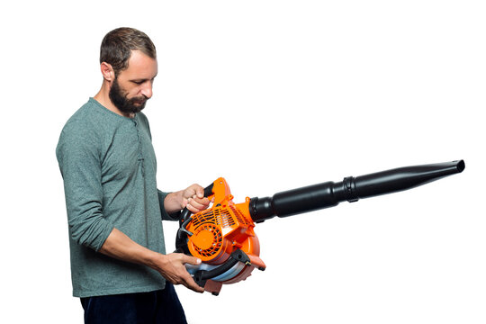 The Worker Holds A Blower In His Hands, Isolated On White Background. Man On A Studio With A Leaf Blower. Handheld Blowing Leaves Away. Tools. Gardening. Machine. Orange Blower Machine With Black Tube