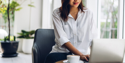 Portrait of smiling happy beautiful asian woman relax using technology of laptop computer sitting on chair.Young hipster asian girl freelancer business thinking with new idea content in cafe
