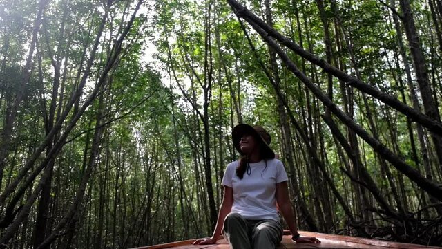 A young asian woman sitting on a long tail boat while traveling the mangrove forest