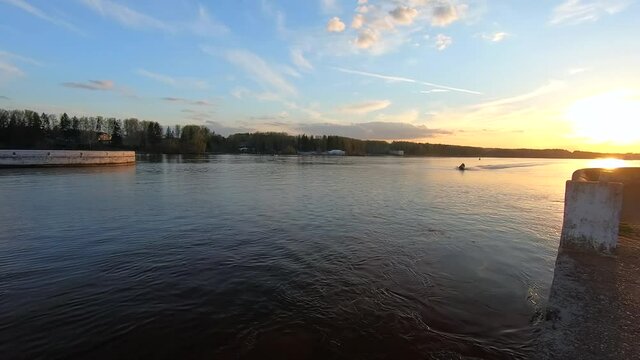 Passing the yacht along the river at sunset. Beautiful colorful landscape of the river against the background of the blue sky at sunset. Traveling by ship on the river