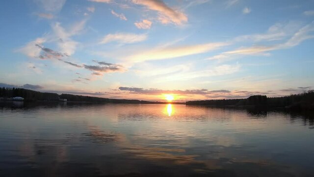 Timelapse colorful sunset. Beautiful panoramic landscape of the river and forest at sunset in orange and blue tones.