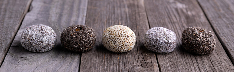 Raw energy bites balls prepared with natural ingredients on old rustic wooden background