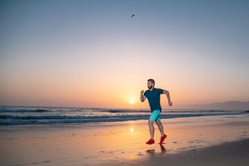 Runner man on the beach be running for exercise. Active healthy runner jogging outdoor. Young man training on the beach in morning.