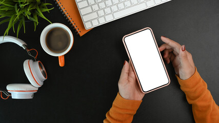 Above view of stylish woman holding mock up smart phone over black leather.