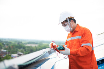 An electrician is holding a digital multimeter into an electrical wire to measure the solar AC voltage.