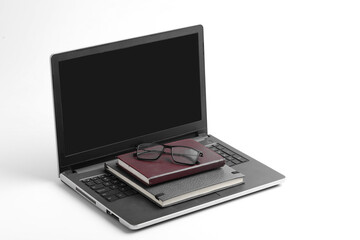 Modern workspace with laptop keyboard, notebook, spectacles on white background.