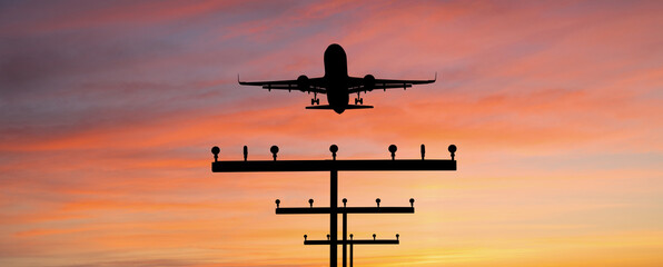 Silhouette of a plane landing at the airport against the background of sunset	
