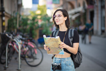 Woman standing on street with map in hands.