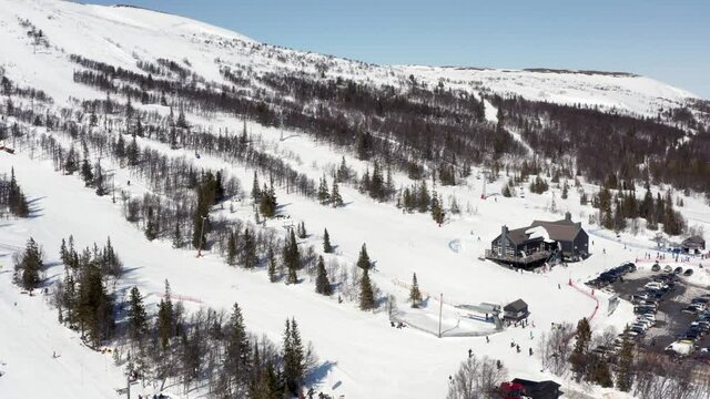 Ski slopes in Sweden on a bright sunny day in winter spring. Aerial rotating view over people and lift