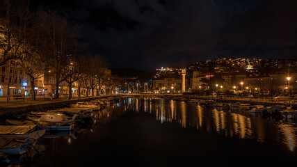Landscape view of Dead canal, Delta of Rjecina river. Old fishing boats tied to the shore with calm sea and reflection shore. Rijeka, Night in Croatia..