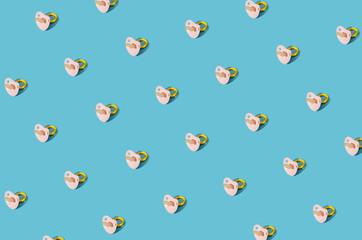 Creative children and babies pattern made of a pacifier on blue background. Minimal concept idea.