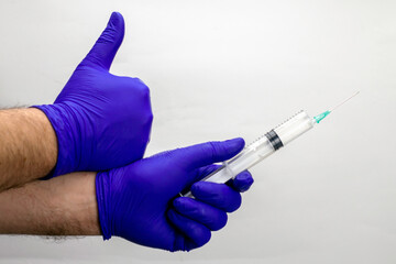 the concept of vaccination hands in blue medical gloves hold a syringe and show the like