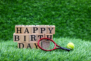Tennis birthday with tennis ball and happy birthday are on green grass background