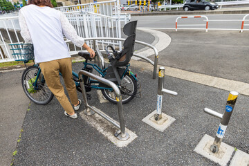 自転車専用路に設置された自動車・バイク進入防止のための柵を自転車を押して通り抜ける女性