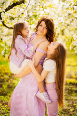 Fototapeta premium A family in a blossoming spring garden. Happy mom and two daughters.