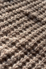 Diagonal close up of a large knitted jumper with an English knit. Natural and beige atmosphere 