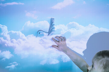 Child holding paper dove against the background of clouds as a sign of peace