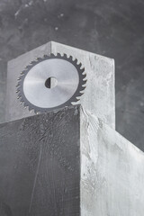Circular saw blade at concrete cube block near wall background texture. Construction concept design