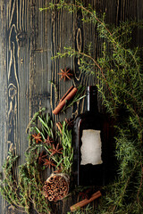 Vintage bottle, herbs, and spices on an old wooden table.