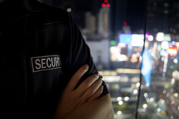 Security guard looking down city full of lights at night..