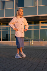 Fototapeta na wymiar Cute stylish European girl of 7 years on the background of an urban building.