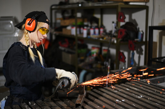 Photo of young woman with angle grinder working in protection in garage - Powered by Adobe