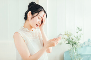 スマホを見て悩む女性（体調不良）

