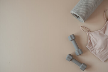 Aesthetic creative flat lay of yoga, fitness, workout training equipment on neutral beige background. Dumbbells, top, mat. Flatlay, top view sport influencer concept