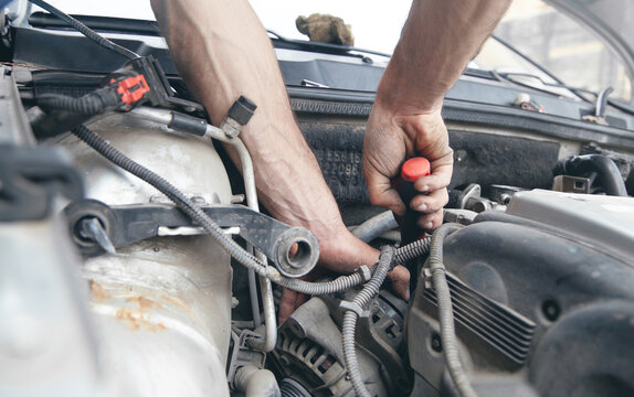 Mechanic repairing car with ratchet wrench.