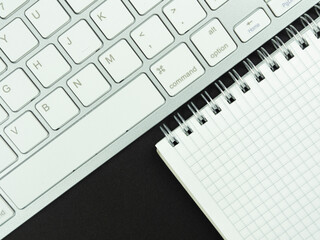 Top view above of  workplace with a white keyboard on the black background. Copy space for your text, Flat lay. Office work and office conception.
