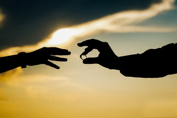 A silhouette shot of a couple exchanging rings during sun set. Stock photography.