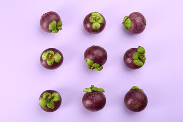 Fresh ripe mangosteen fruits on light violet background, flat lay
