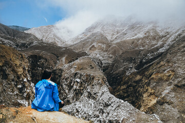 Woman sitting on top of a mountain enjoying the surrounding.