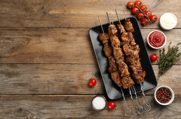 Metal skewers with delicious meat and vegetables served on wooden table, flat lay. Space for text