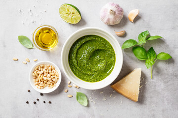 Fresh Italian pesto sauce with basil, pine nuts, parmesan cheese and olive oil on the light gray background. Top view 