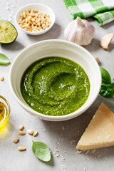 Fresh Italian pesto sauce with basil, pine nuts, parmesan cheese and olive oil on the light gray background. 