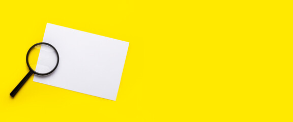 magnifying glass and blank white sheet on a yellow background. Banner