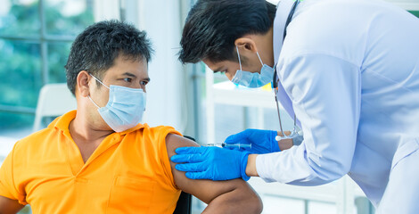 Middle age Asian man seriously looking at doctor while giving injection Coronavirus or Covid-19...