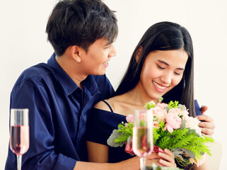 A cute young and beautiful long hair Asian woman feels shy when the man gives her rose bouquet