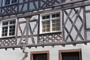Closeup of an old half-timbered house facade with lattice windows and an ancient lantern