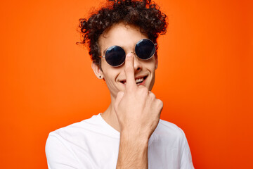 man in white t-shirt modern style orange background glasses in hands